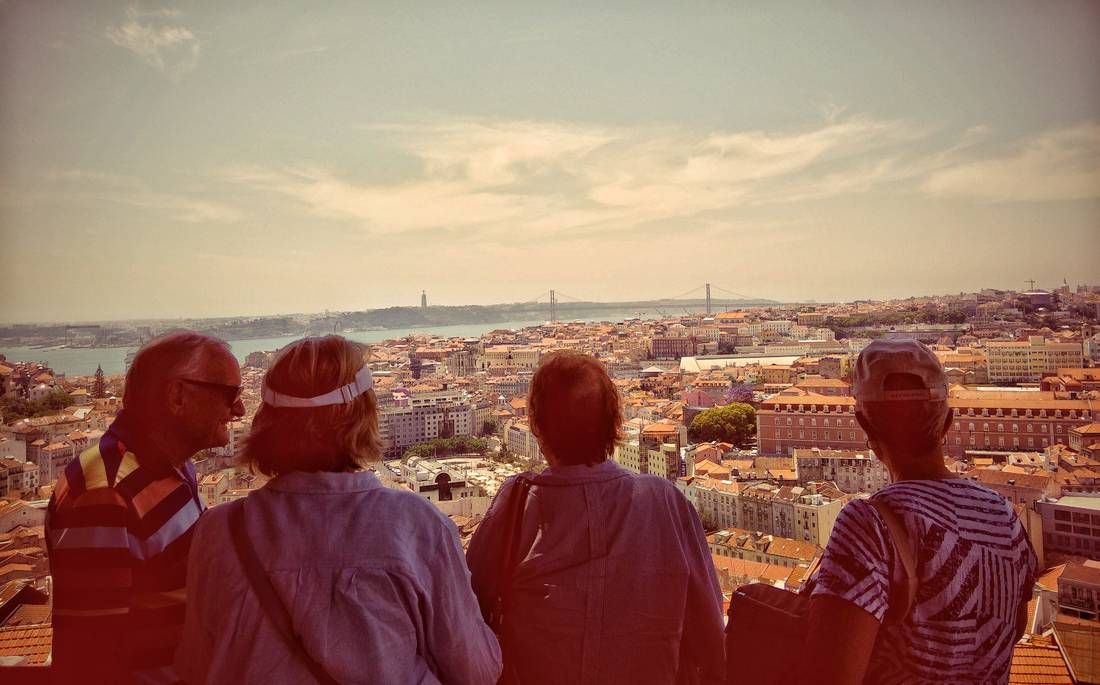 A small group at a Lisbon viewpoint looking over the rooftops toward the Tagus