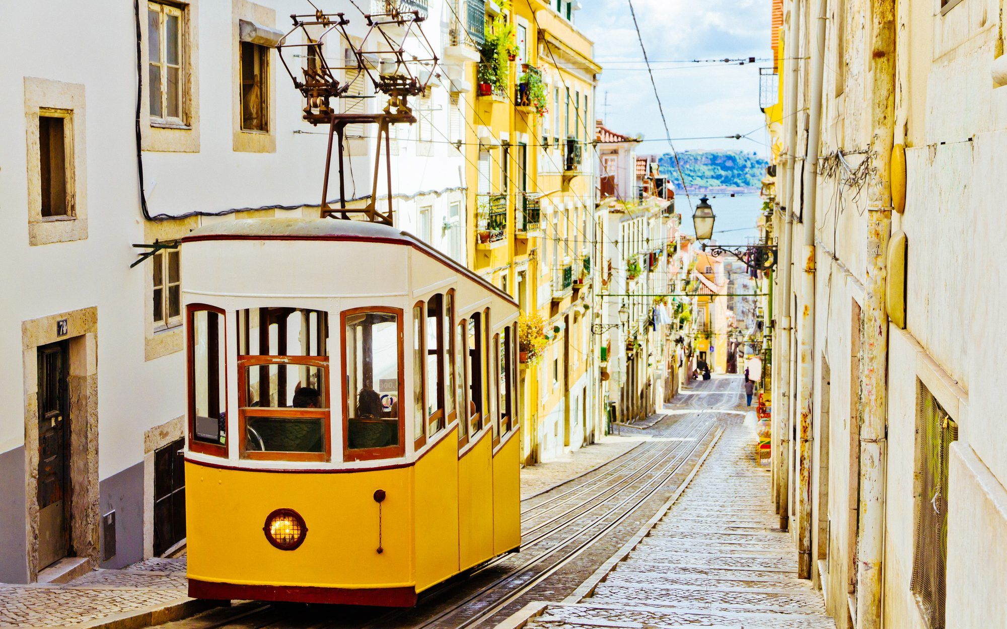 Un tramway jaune traditionnel gravissant une rue en pente de Lisbonne