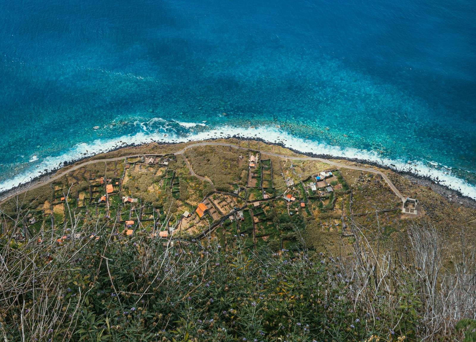 A small terraced village on Madeira's coastline, seen from the cliffs above