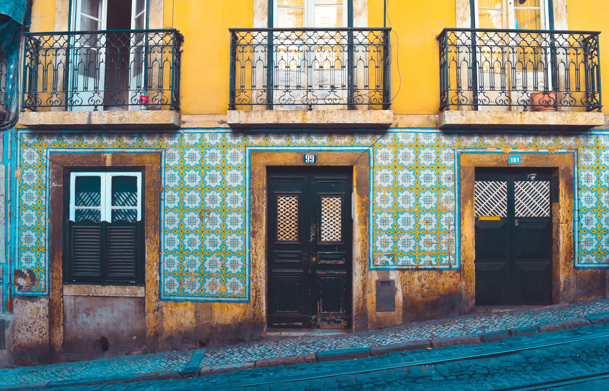 Une maison lisboète couverte d'azulejos dans une rue pavée aux rails de tramway