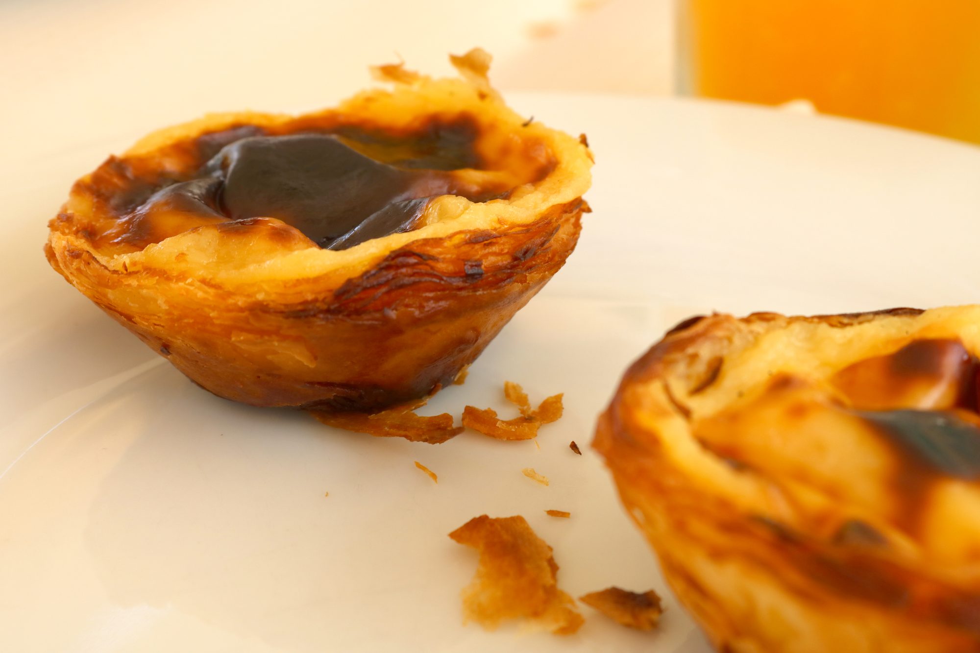 Three pastéis de nata dusted with cinnamon on a Pastéis de Belém plate